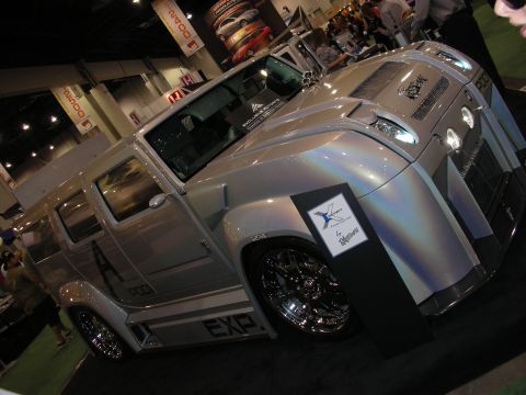 1998 Ford Crown Victoria - silver custom vehicle with large chrome wheels and 'EXP' graphics sits on display at an indoor automotive expo.