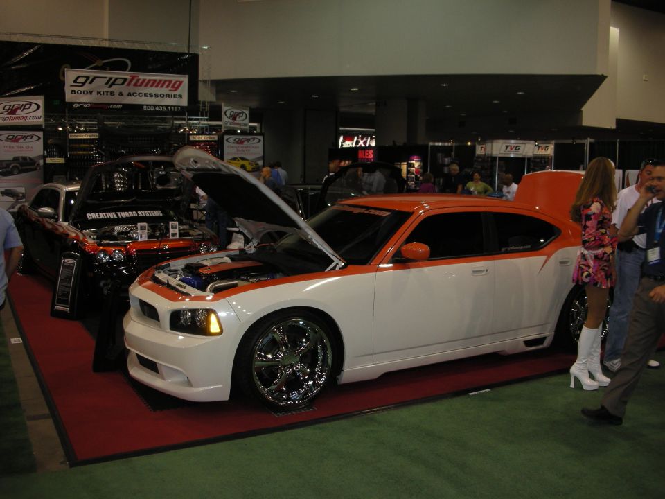 White Dodge Charger with orange stripes and open hood at automotive trade show