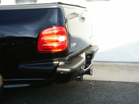 2001 Mercury Grand Marquis - The rear of a black pickup truck is shown parked in front of a garage door.