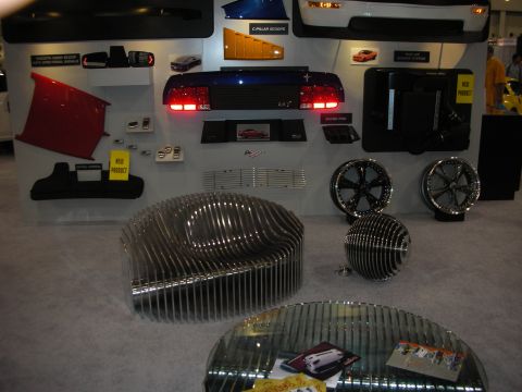 1998 Ford Crown Victoria - vendor display wall presents car body panels, taillight assemblies and polished wheels above brushed-metal decorative sculptures.