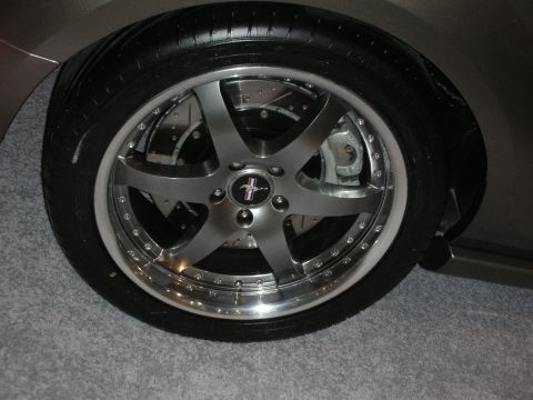 1998 Ford Crown Victoria - Close-up of a gunmetal five-spoke wheel with a polished outer lip and exposed brake caliper on a low-slung vehicle.