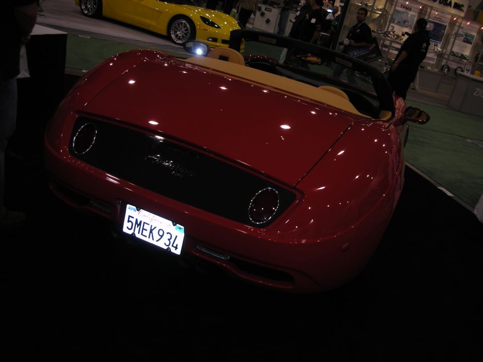 Rear of red convertible roadster with California plate '5MEK934' at indoor show