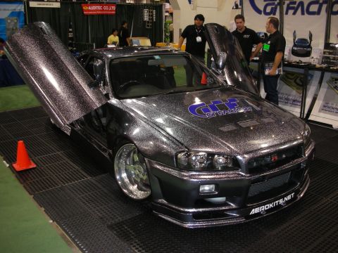 1998 Ford Crown Victoria - sparkle-flake Nissan Skyline GT-R with a vertical-opening door and GT-R badge sits on display at an auto tuning exhibition.