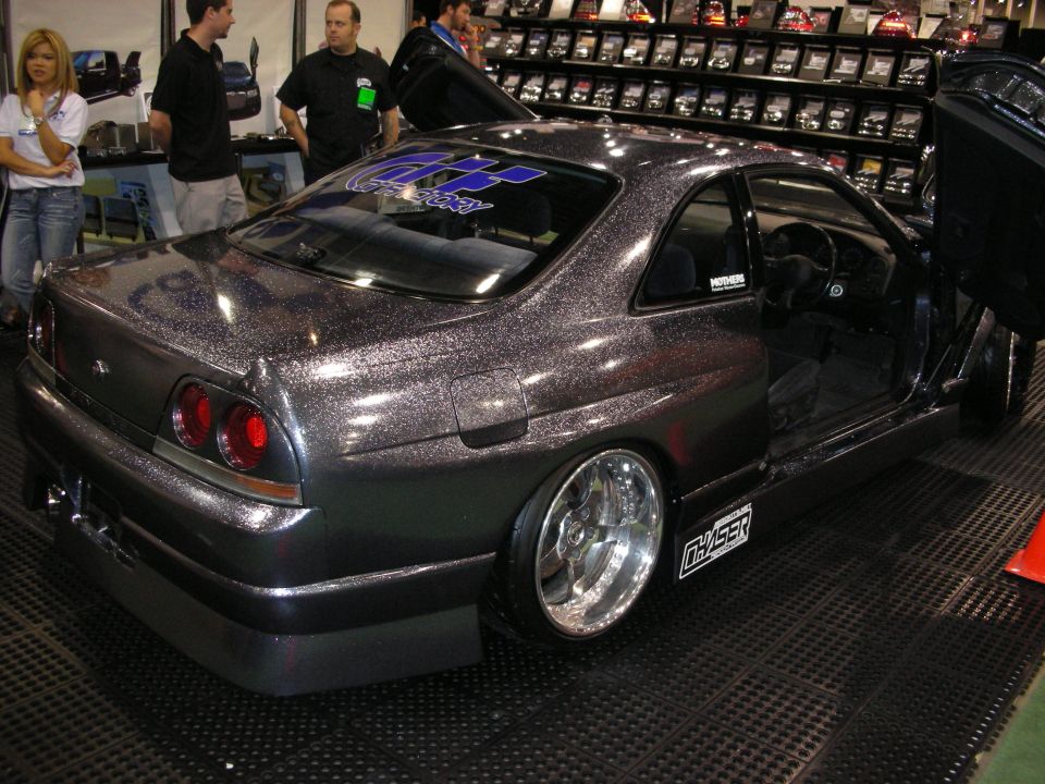 Rear three-quarter of metallic-flake Nissan Skyline coupe with deep chrome wheels