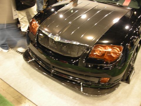1998 Ford Crown Victoria - Low-angle front view of a black Chrysler Crossfire showing its carbon hood, chrome winged grille badge and carbon front splitter.