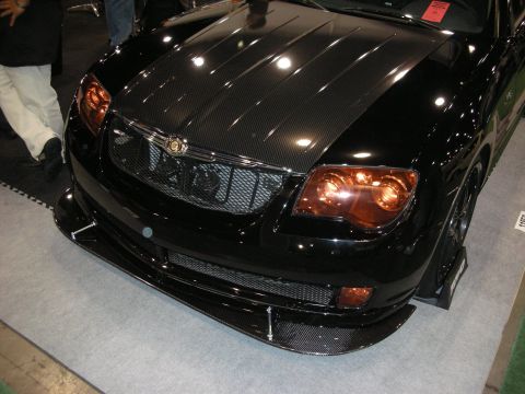 1998 Ford Crown Victoria - Black Chrysler Crossfire displayed front-three-quarter, showing its carbon-fiber hood, amber headlights and carbon front splitter.