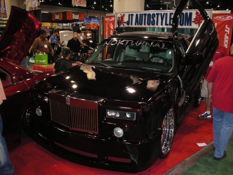 1998 Ford Crown Victoria - black custom Rolls-Royce Phantom lettered 'Nokturnal' with vertical doors and chrome wheels on display at the JT Autostyle booth.