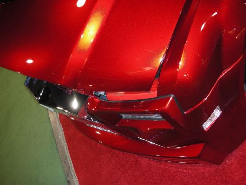 1998 Ford Crown Victoria - Detail of a candy-red metallic custom front fender and recessed headlight assembly displayed over red carpet.