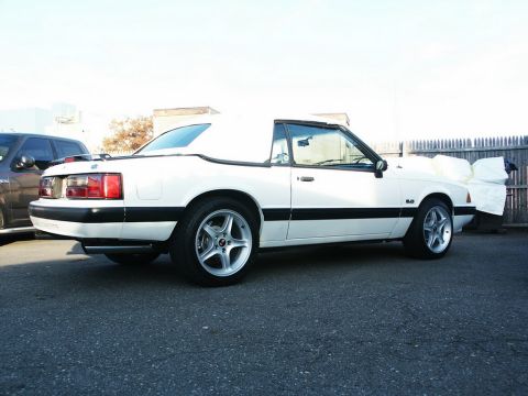 2001 Mercury Grand Marquis - A white convertible sports car is parked outdoors next to a dark SUV.