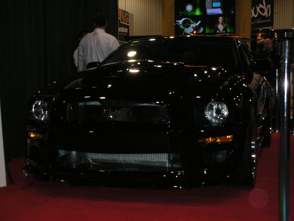 Front of a glossy black modified coupe under dim show lighting