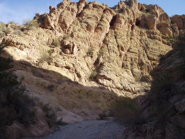 Gravel wash trail through a tan and red desert canyon with scrub brush