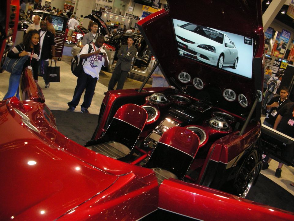 Candy-red car with open hatch, speaker array and video screen