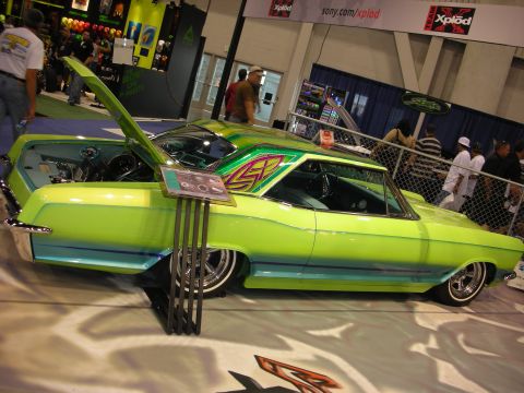 1998 Ford Crown Victoria - lowered lime-green classic coupe with airbrushed graphics and chrome wheels displayed on a white floor at the Sony Xplod booth.