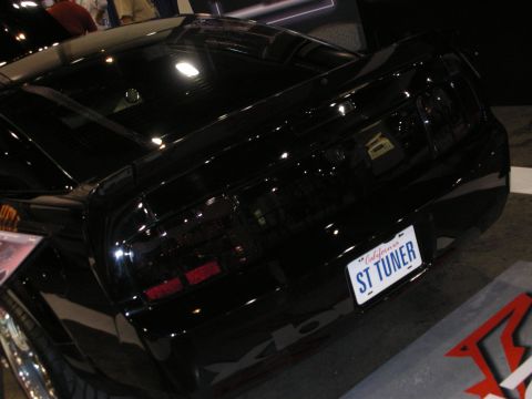 1998 Ford Crown Victoria - Rear three-quarter of a glossy black custom car with smoked taillights and a California 'ST TUNER' license plate.