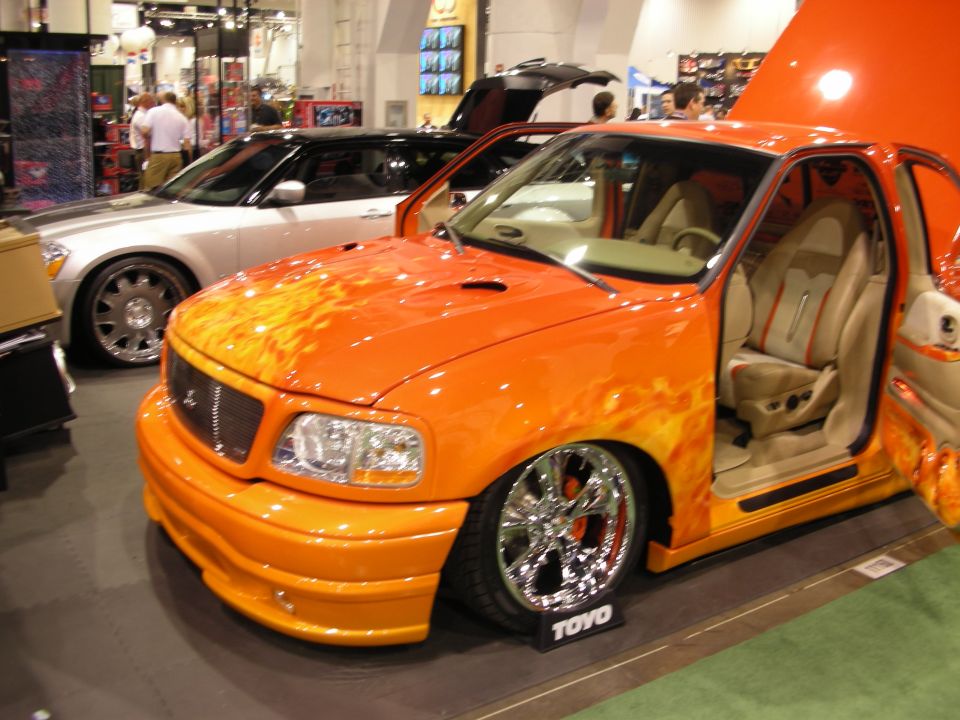 Orange flame pickup with open suicide door and tan interior at show