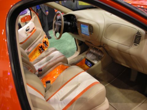 1998 Ford Crown Victoria - Custom pickup interior in tan leather with orange flame accents, a dash-mounted screen and bucket seats viewed through the door.