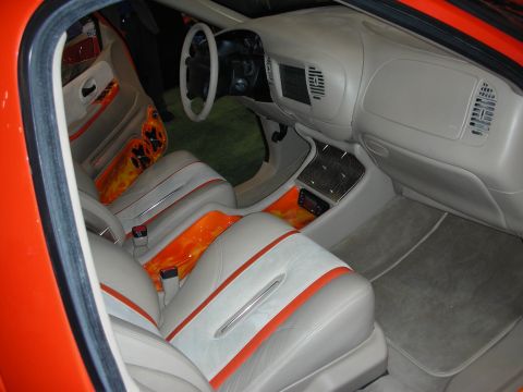 1998 Ford Crown Victoria - Custom pickup interior in gray leather with orange flame trim, console-mounted screen and matching bucket seats.
