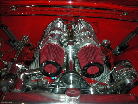 1998 Ford Crown Victoria - heavily polished engine bay with twin superchargers, red conical air filters and a Chevrolet bowtie on the timing cover, set in a red engin…