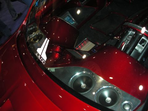 1998 Ford Crown Victoria - candy-red custom trunk install with JL Audio subwoofers and a mirrored amplifier display under a tinted cover.