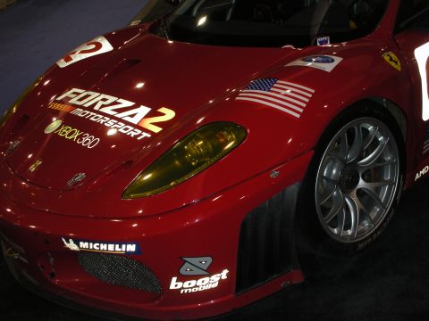 1998 Ford Crown Victoria - front corner of a red Ferrari GT race car wearing Forza Motorsport 2 and Xbox 360 livery with Michelin and a U.S. flag decal.