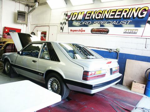 2001 Mercury Grand Marquis - A silver Ford Mustang GT is positioned on a dynamometer inside a workshop, with a banner for 'JDM ENGINEERING' visible on the wall.