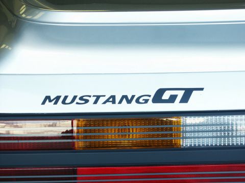 2001 Mercury Grand Marquis - Close-up of a car's rear, showing the 'MUSTANG GT' emblem and taillight assembly.