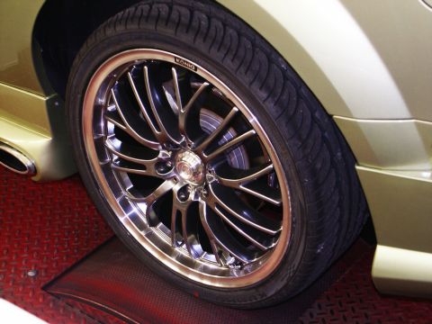2001 Mercury Grand Marquis - A custom chrome wheel and tire are shown on a gold vehicle, possibly on a dynamometer.