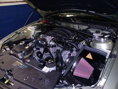 2001 Mercury Grand Marquis - The engine bay of a silver 2005 Ford Mustang GT shows a V8 engine with an aftermarket air intake system.