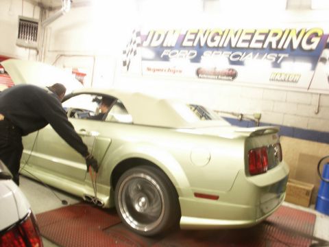 2001 Mercury Grand Marquis - A light green convertible sports car is on a dynamometer in a garage with 'JDM ENGINEERING' and 'FORD SPECIALIST' banners visible.