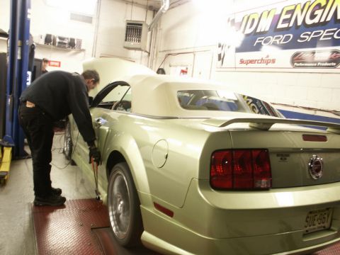 2001 Mercury Grand Marquis - Mechanic works on a light green convertible Mustang on a dynamometer in a garage.