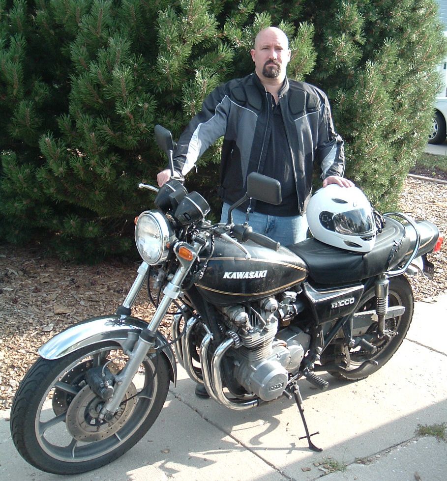 Black Kawasaki KZ1000 motorcycle, left side, man with white helmet behind it