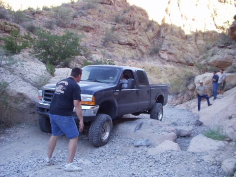 1993 Ford Bronco - A dark-colored Ford F-250 pickup truck navigates a rocky, off-road path in a canyon.