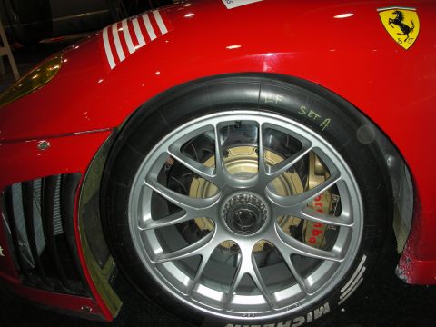 1998 Ford Crown Victoria - close-up of a silver multi-spoke racing wheel, Michelin tire and yellow brake caliper on a red Ferrari with prancing-horse badge.