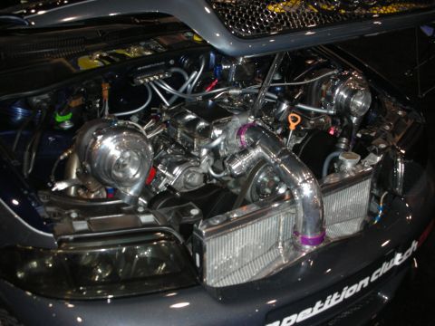 1998 Ford Crown Victoria - twin-turbo engine swap with large intercooler, polished charge piping and a Competition Clutch decal on a dark car's front bumper.