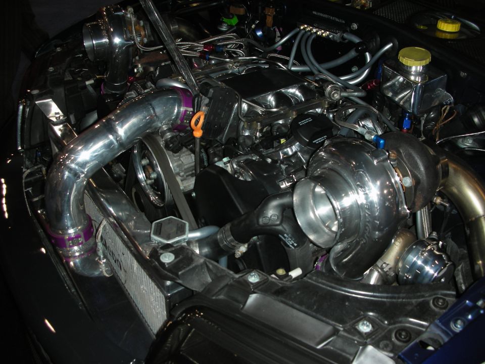 Polished twin-turbo engine bay with chrome piping in dark sports car