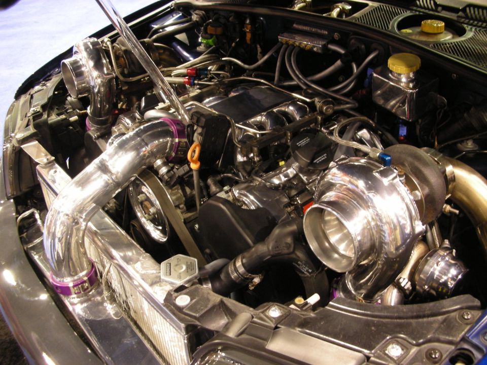 Polished twin-turbo engine with chrome intake piping in dark engine bay