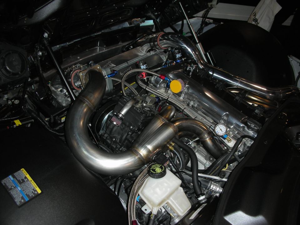 Polished stainless turbo manifold and piping in a dark engine compartment
