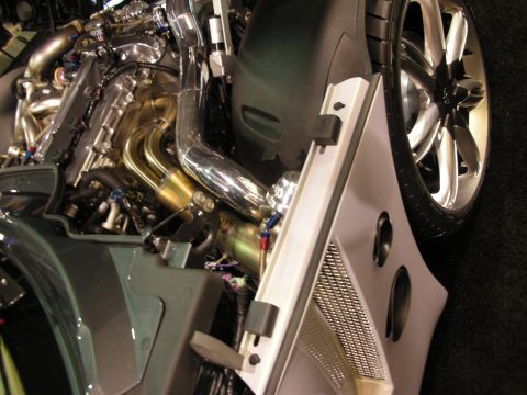 1998 Ford Crown Victoria - polished engine with gold tube headers and chrome charge pipe above a chrome multi-spoke wheel on a green show car.