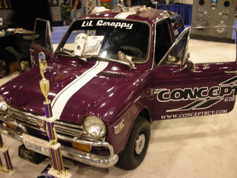 1998 Ford Crown Victoria - purple vintage compact pickup labeled Lil Scrappy with a white racing stripe, Concept Audio decals and a trophy beside it.