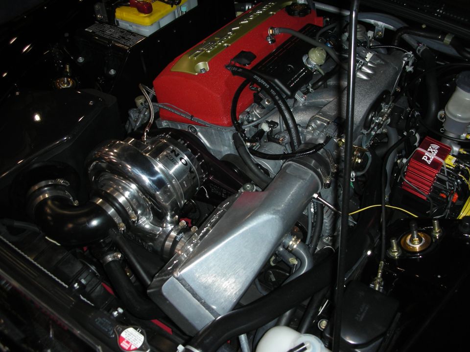 Close-up of a chromed supercharger or turbo on a red-topped engine