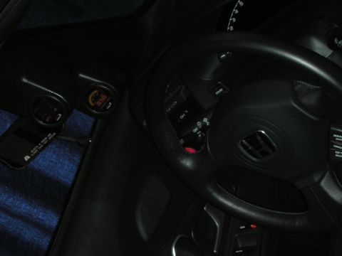 1998 Ford Crown Victoria - dimly lit interior shows a Honda H-badged steering wheel, column stalks and dashboard with a small mirror-mounted device.