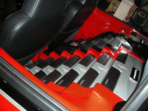 1998 Ford Crown Victoria - red custom trunk install displays a row of angled black-and-silver car audio amplifiers beside a leather seat back.