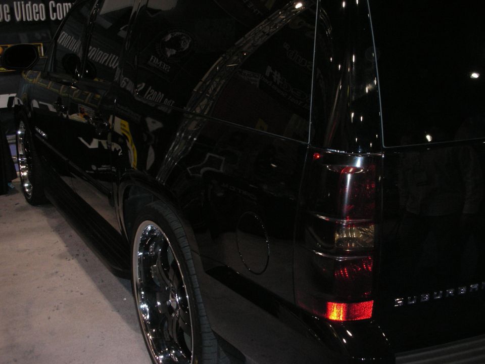 Rear quarter of a black SUV with chrome wheels at a show