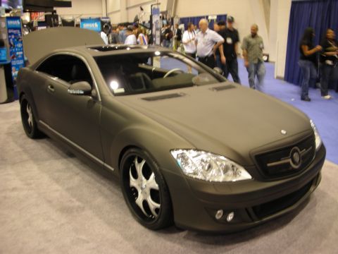 1998 Ford Crown Victoria - front-quarter view of a matte-grey Mercedes-Benz coupe with custom grille and chrome wheels on a blue carpet at a show.