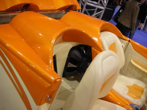 1998 Ford Crown Victoria - glossy orange-and-cream custom convertible shows its sculpted bodywork and white leather seats at an indoor show.