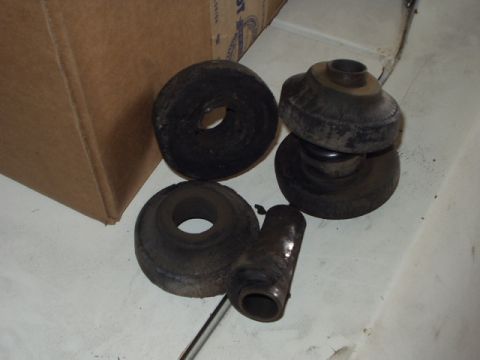 Several rubber and metal suspension components, possibly bushings and a shock absorber mount, next to a cardbo