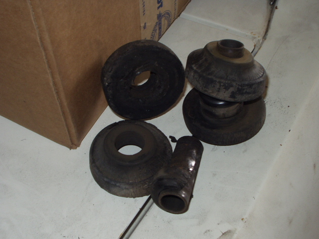 Several rubber and metal suspension components, possibly bushings and a shock absorber mount, next to a cardboard box