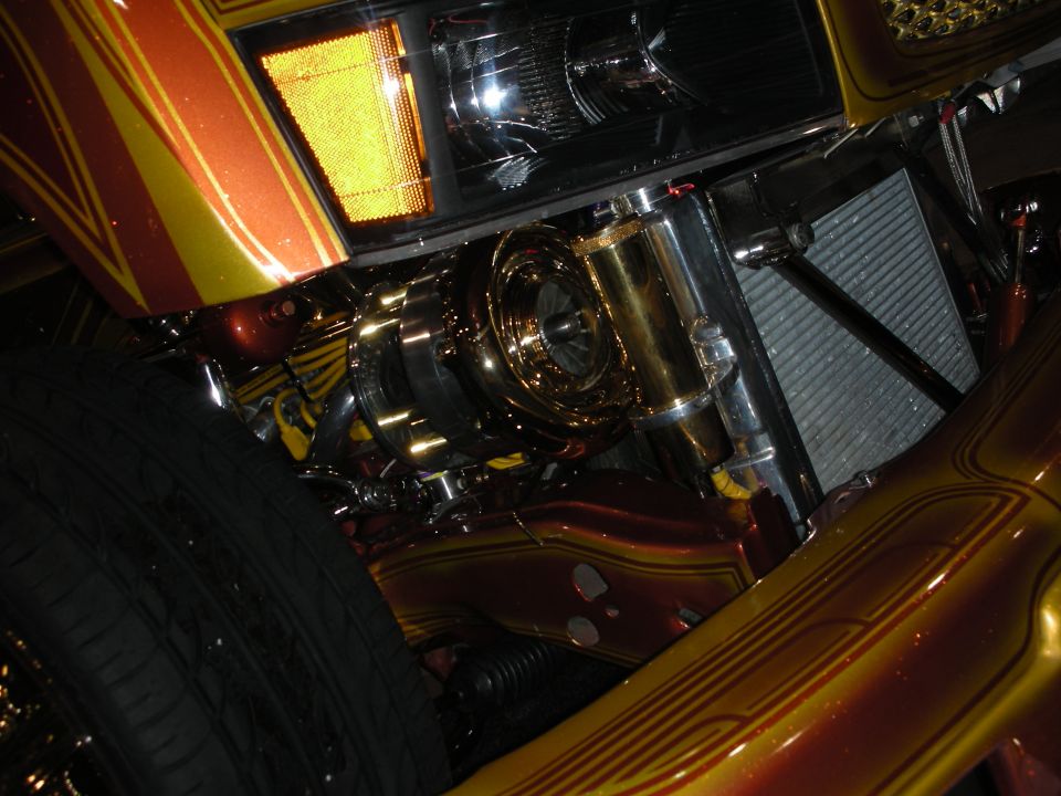 Close-up of gold-plated engraved engine parts on a candy-painted car