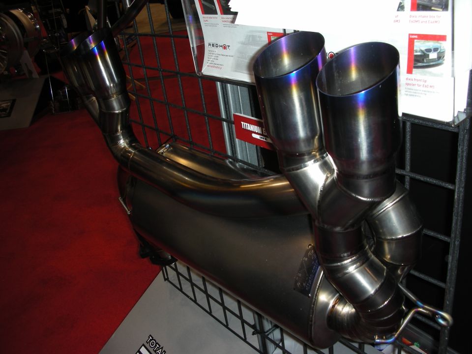 Titanium exhaust system with burnt-blue dual tips on a display stand