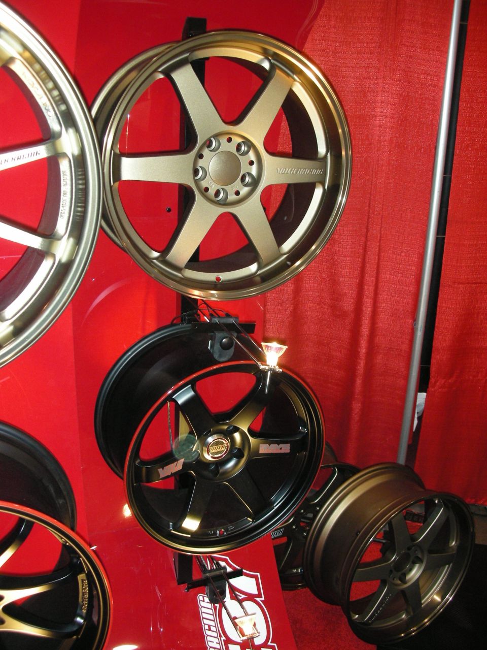 Bronze and black six-spoke wheels mounted on a red booth wall